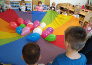 Dzieci bawią się chustą animacyjną i balonami.